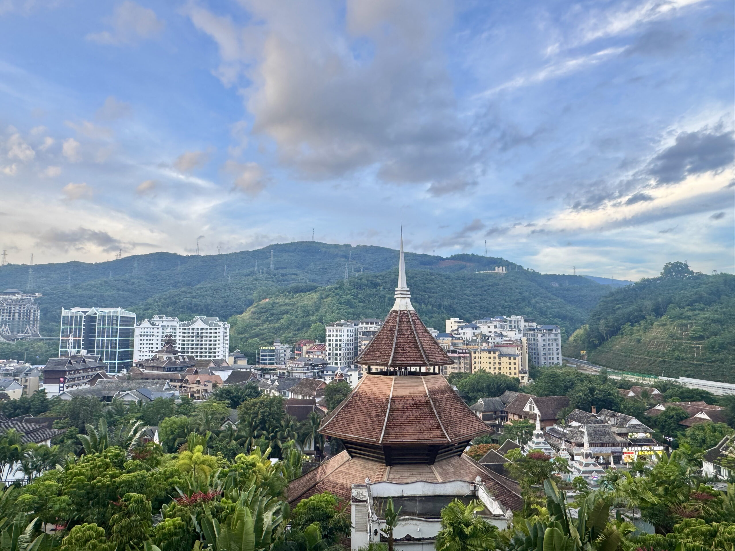 A view of the city of Jinghong, China, with green mountains and leafy tropical trees