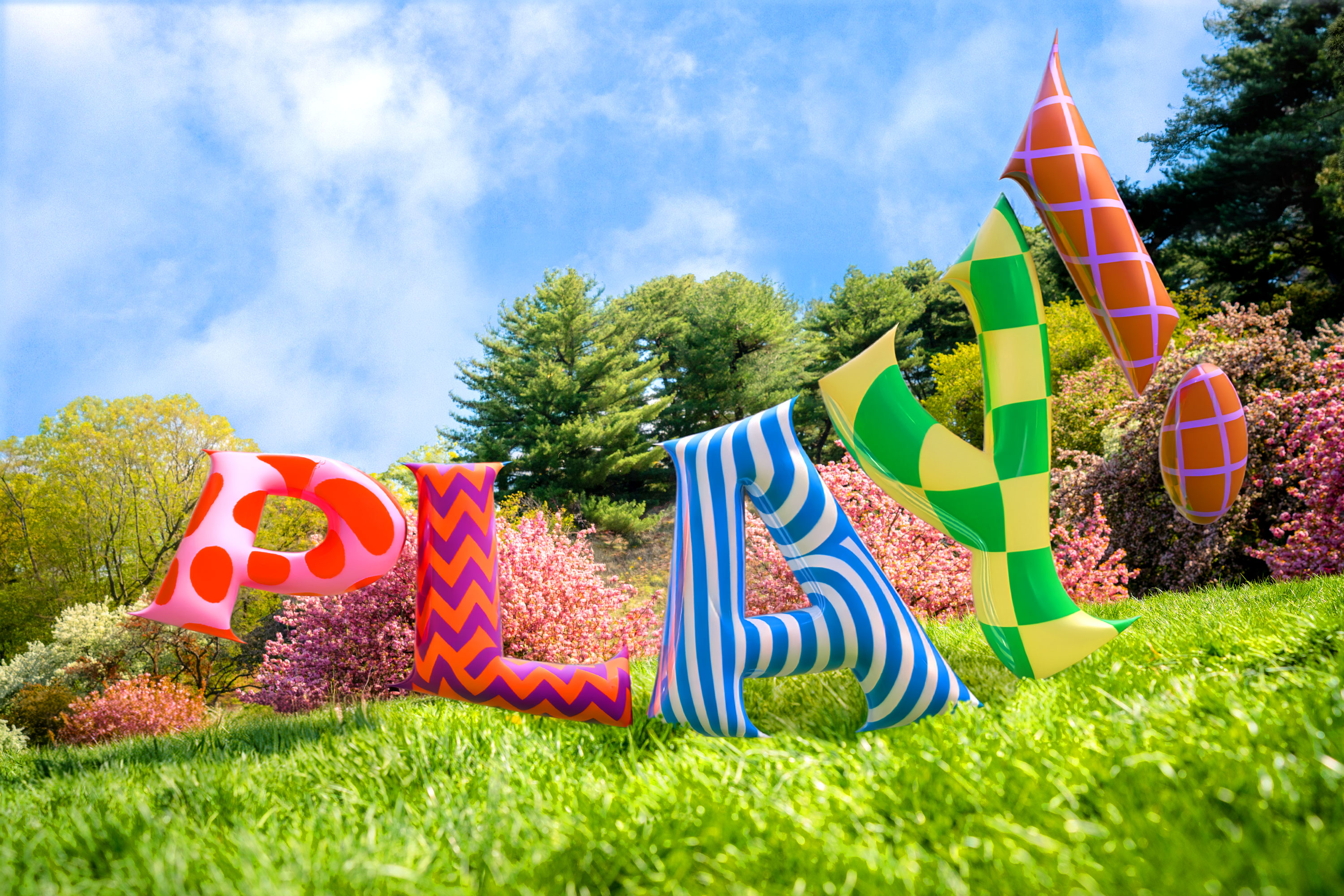 A colorful balloon display of the word "PLAY!" floating in a sunny green field