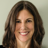 A person with long brown hair poses for a headshot