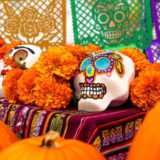 A photo of colorful sugar skulls among orange flowers