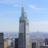 A photo of a towering silver skyscraper in a daylight city setting