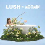 A person sits in a bathtub surrounded by white flowers and green moss, with the words Lush x Moomin in white lettering above on a blue background