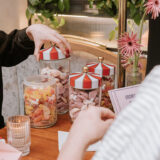 People open jars of gummy candies on a table, each with a red and white cap shaped like a circus tent