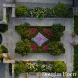 A top-down aerial photo of an elegantly planted garden featuring plants in green, red, and pink