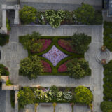 A top-down aerial photo of an elegantly planted garden featuring plants in green, red, and pink