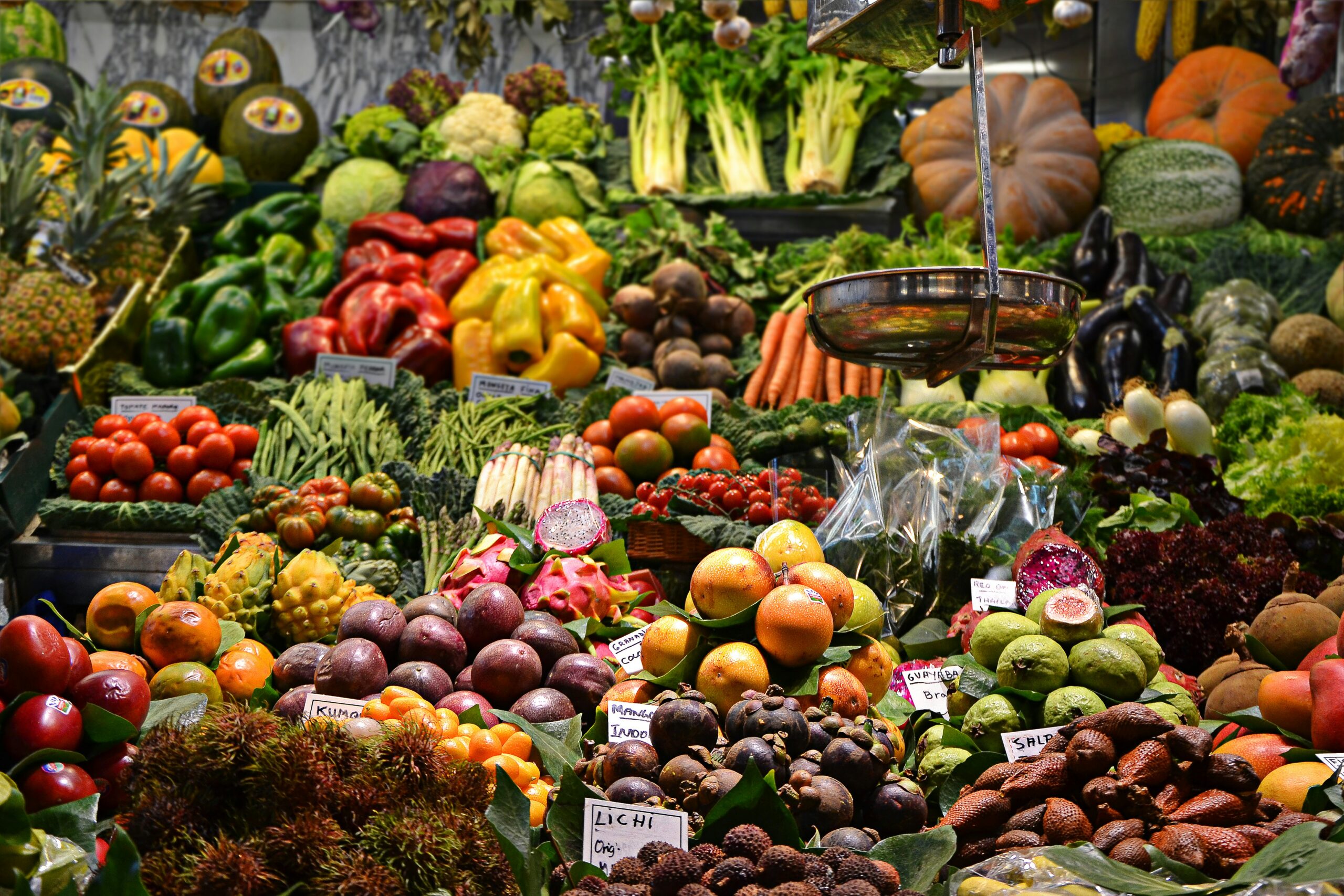 A market display of dozens of varieties of fruits and vegetables arranged under warm lighting