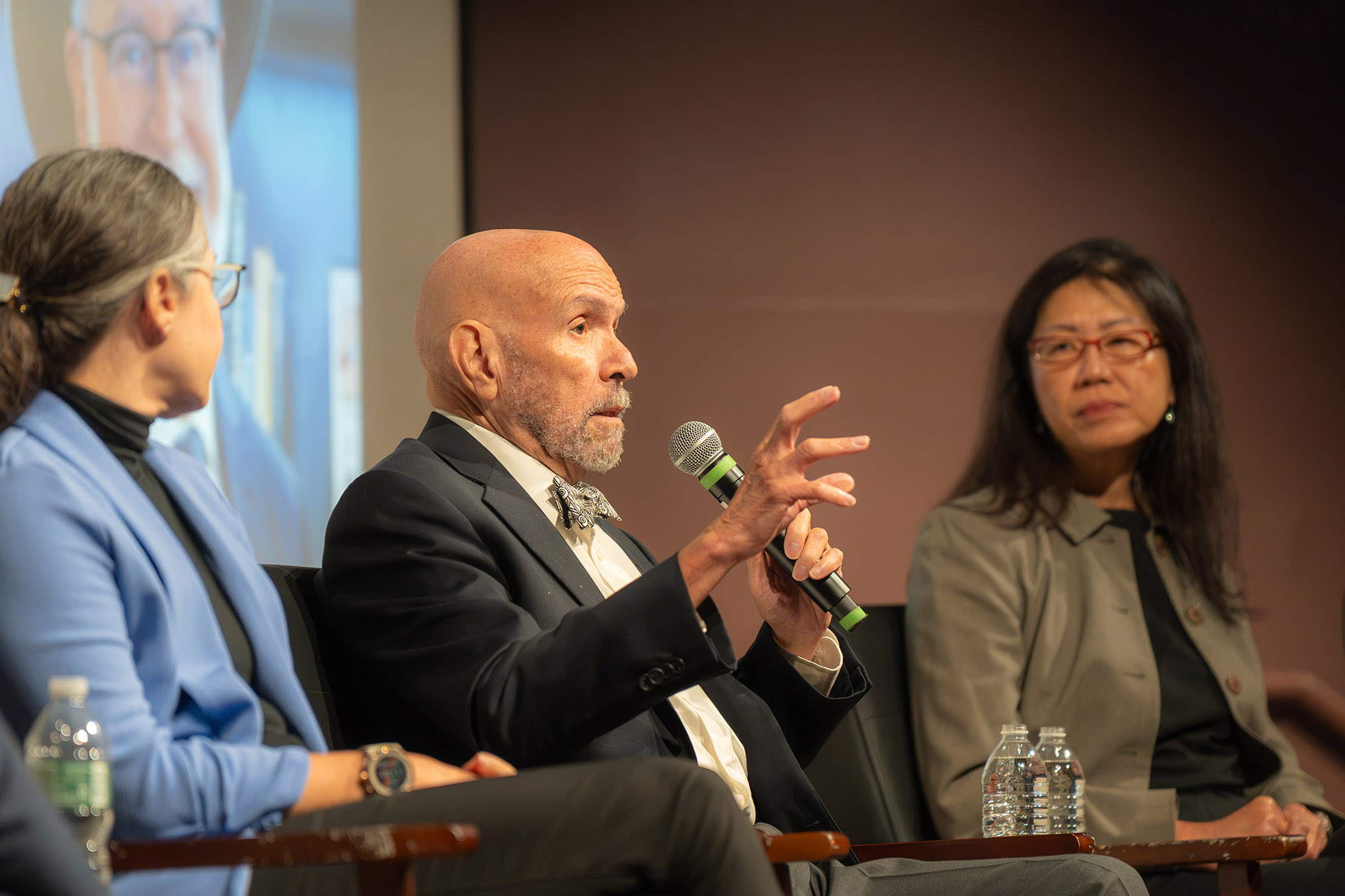 Four people sit in chairs on a lit stage for a panel discussion
