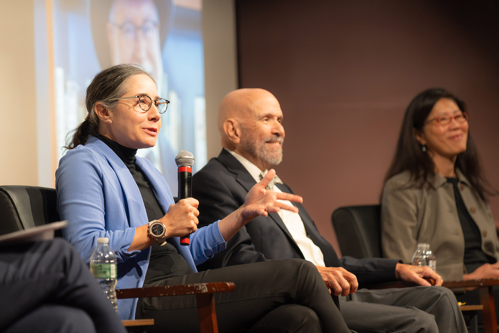 Four people sit in chairs on a lit stage for a panel discussion