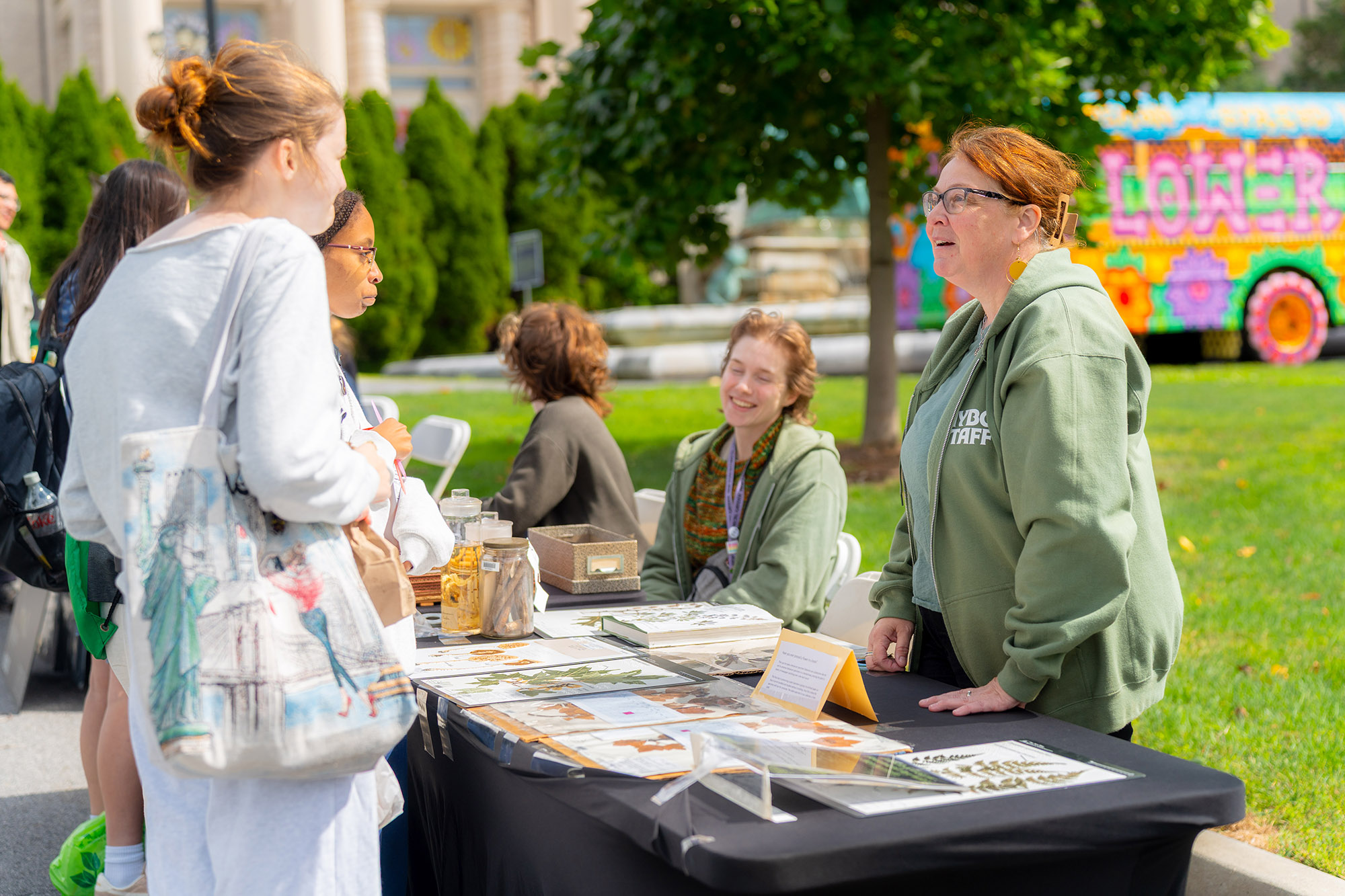 People at a table outside share information with visiting guests