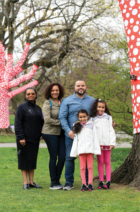 A Bronx elected official and his family pose for a photo beneath a pair of trees on NYBG s grounds, each one wrapped with whimsical red and white cloth 