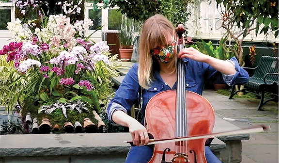 A person sits while playing a cello in the Aquatic House of the Enid A  Haupt Conservatory 